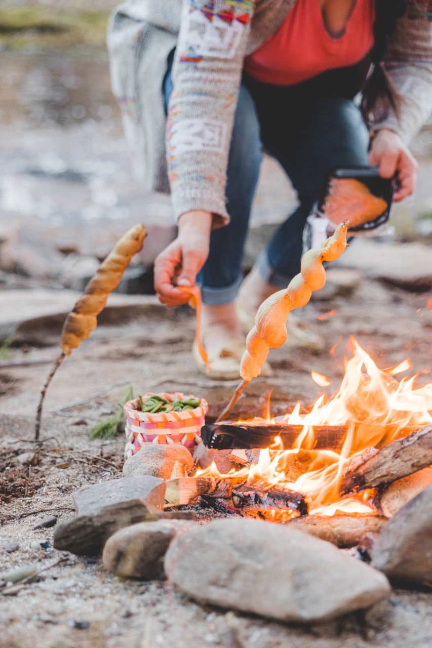 Photo of person cooking bannock over a fire